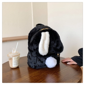 Detail of cute black faux fur backpack with long white bunny ears and golden zipper