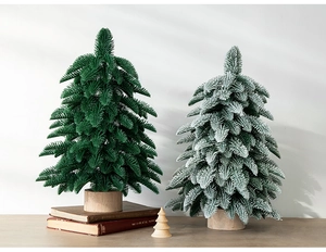 Mini PE Christmas trees with snow effect and natural wood base on a cozy wooden table