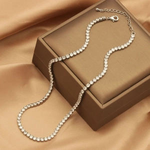 Detailed shot of silver-plated zircon tennis necklace on premium golden satin background