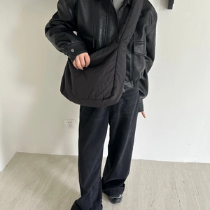 Large black padded nylon tote bag for women worn by model in a minimalist urban setting