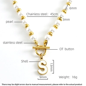 Détail du collier de perles en acier doré avec pendentif lettre S et fermoir OT