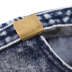 Macro shot of durable washed denim fabric and vintage brass buckle on baseball cap