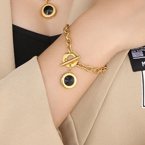 Detail of gold OT buckle bracelet and matching necklace with black round stones on model