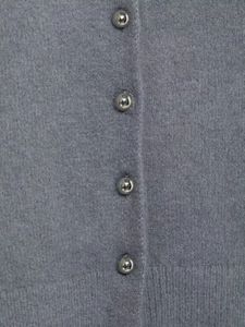 Dettaglio del cardigan in maglia grigia con trama lanosa e bottoni sferici in metallo