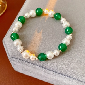 Dettaglio di bracciale vintage con perle bianche, grani verdi e distanziatori in metallo
