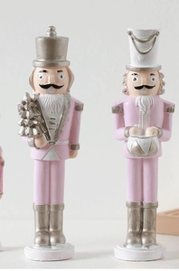 Detail of pink and silver nutcracker figures holding a Christmas tree and drum