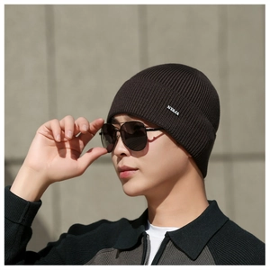 Détail d'un bonnet en maille côtelée marron foncé pour homme avec logo métallique élégant