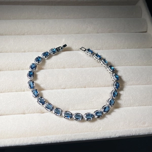 Close-up of silver bracelet with oval blue gemstones and halo diamonds in jewelry box
