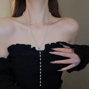 Gros plan du collier en Y double épaisseur avec perles et pompon sur le mannequin