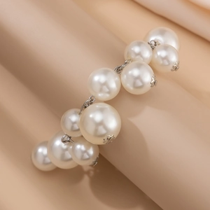 Macro shot of white imitation pearls and silver metal chain on a silk fabric background