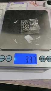 Detailed view of stainless steel cross necklace weight on digital scale at 33.7 grams