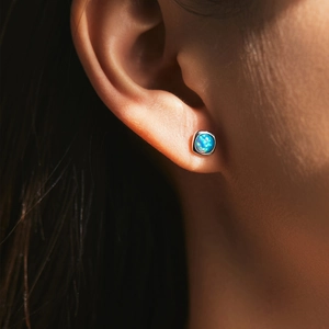 Minimalist s925 silver square stud earrings with shimmering blue opal stone on ear lobe