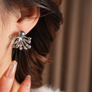 Macro view of flower-shaped pearl earrings with sparkling diamonds on female ear