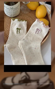 Detail of cream cotton socks with colorful flecks, ruffled edges and cute bows decoration