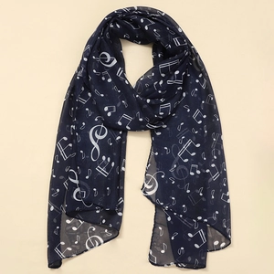 Close-up of lightweight chiffon scarf featuring white musical notes on a navy blue fabric