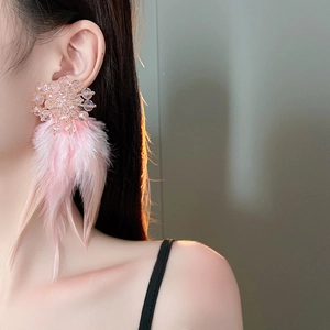 Detail of pink feather tassel earrings with crystal cluster on elegant female model
