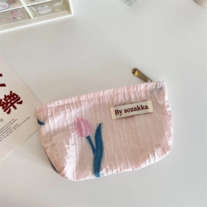 Macro detail of pink floral embossed fabric pouch with tulip print and branded woven label