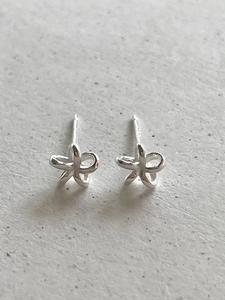 Macro view of small five-petal silver flower stud earrings with a polished metallic finish