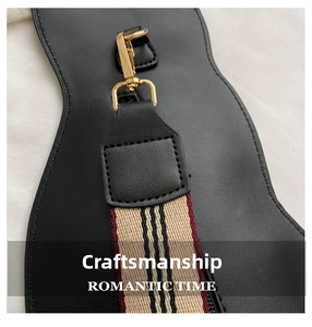 Detail of a black leather saddle bag with gold hooks and iconic plaid fabric strap