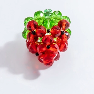 Detail of handmade beaded strawberry pendant with red faceted crystals and green leaf