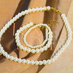 18K gold plated necklace and bracelet set with high luster white pearls on brown background