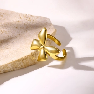 Detailed close-up of a gold butterfly open ring resting on a natural beige stone