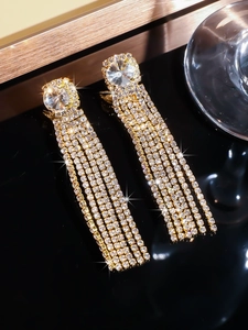 Detail of long gold tassel earrings with sparkling rhinestones and micro-pave zircons