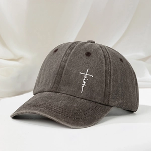 Macro shot of white faith cross embroidery on a washed dark gray vintage baseball cap
