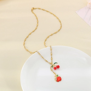 Golden titanium steel necklace with red fruit pendants on a white porcelain plate