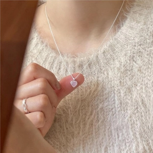Macro detail of a 925 silver heart necklace with a lavender crystal on a soft sweater