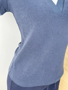 Close-up of blue knit polo shirt featuring a V-neck design and fine ribbed fabric texture