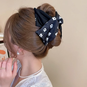 Elegant black floral bow hair clip styled on a bun hairstyle for a sophisticated look