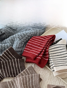 Detail of warm wool blend striped socks in red and brown with cozy knitted texture
