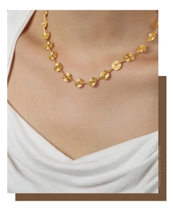 Close-up of golden geometric spiral disc necklace showing elegant drape on the neck