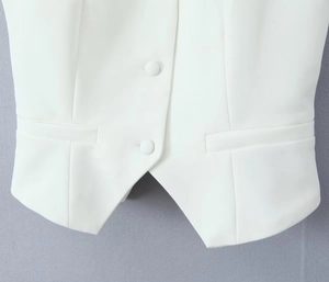 Close-up of white blazer vest featuring single-breasted fabric buttons and pocket detail