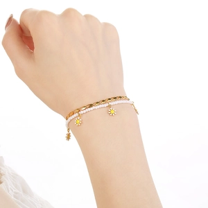 Close-up of double-layer stainless steel daisy bracelet with white beads on wrist