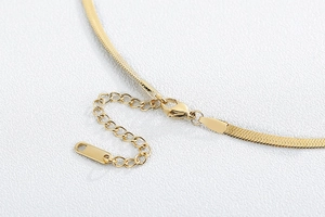 Detail of gold flat snake chain necklace with lobster clasp and adjustable extension link