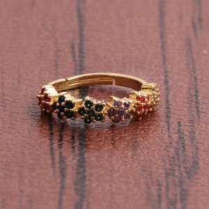 Détail d'une bague fleur en or avec des zircons multicolores sur un fond sombre