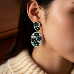 Detail of vintage flower drop earrings with green emerald stones and silver needle studs