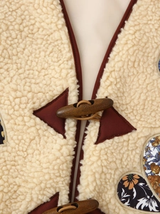 Macro shot of faux lamb wool texture with vintage toggle button and contrast patchwork