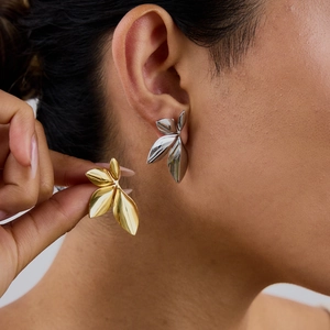Titanium steel leaf-shaped earrings in gold and silver finish shown on a model