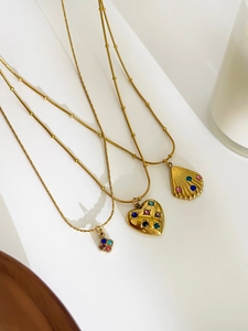 Detailed view of gold necklaces with heart and shell charms featuring multi-color crystals