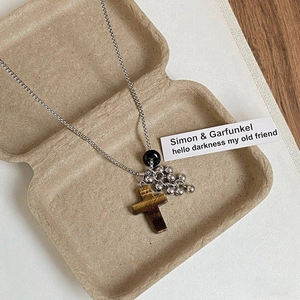 Macro shot of tiger eye stone cross pendant necklace in a vintage aesthetic gift box