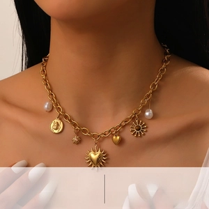 Detailed close-up of gold chunky chain necklace with pearl, sun and heart charms for women