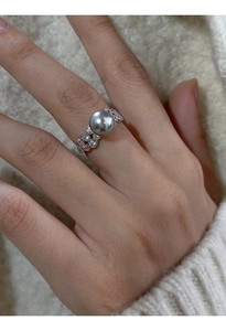 Macro shot of a silver ring with a large grey pearl on a white knit background