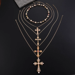 Detailed view of layered gold cross necklaces with pearls and colorful gemstones