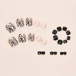 Detailed view of champagne leopard print and black press-on toe nails with golden glitter