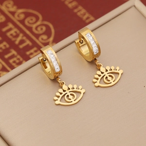 Macro detail of gold evil eye earrings with zircon pavé on vintage background