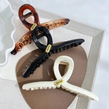Détails de pinces à cheveux torsadées en ambre, noir et beige avec logos dorés
