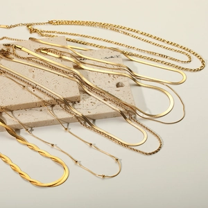 Detail of layered 18k gold plated stainless steel snake and braided chain necklaces